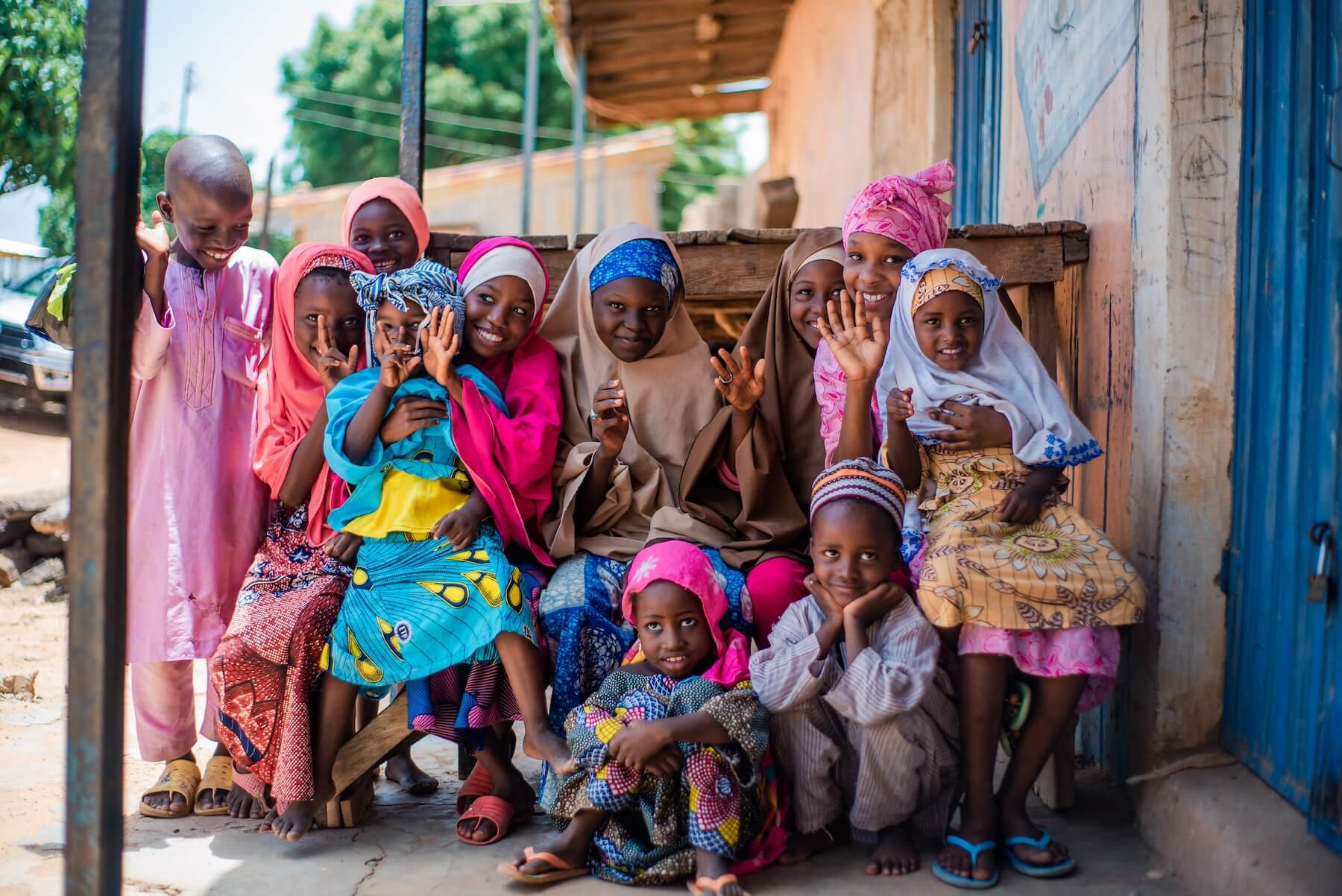 A group of smiling Nigerian children waving at the camera